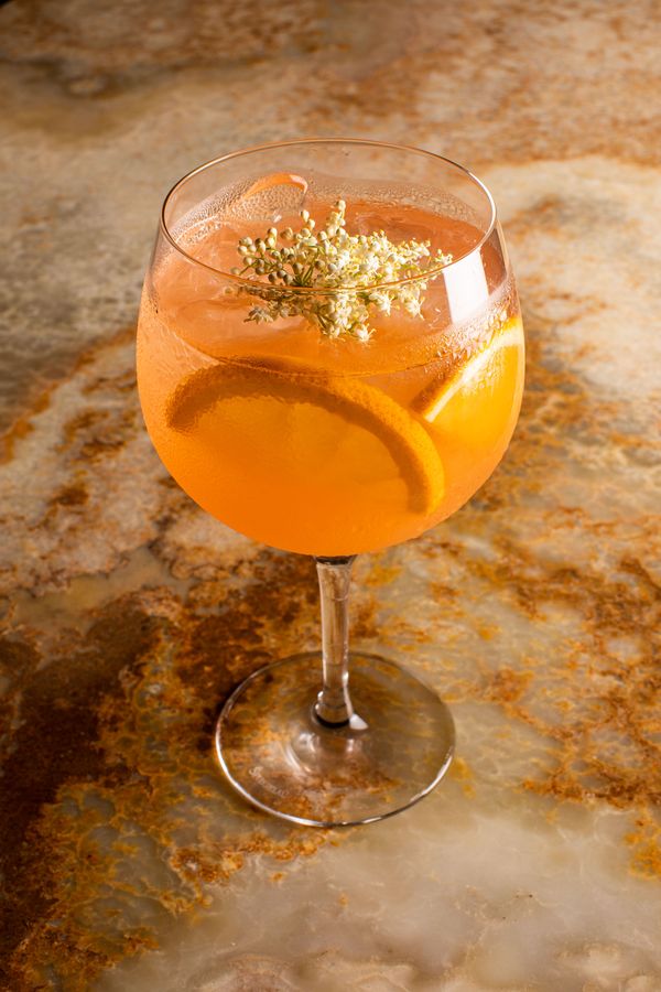 An orange cocktail in a stemmed glass on onyx