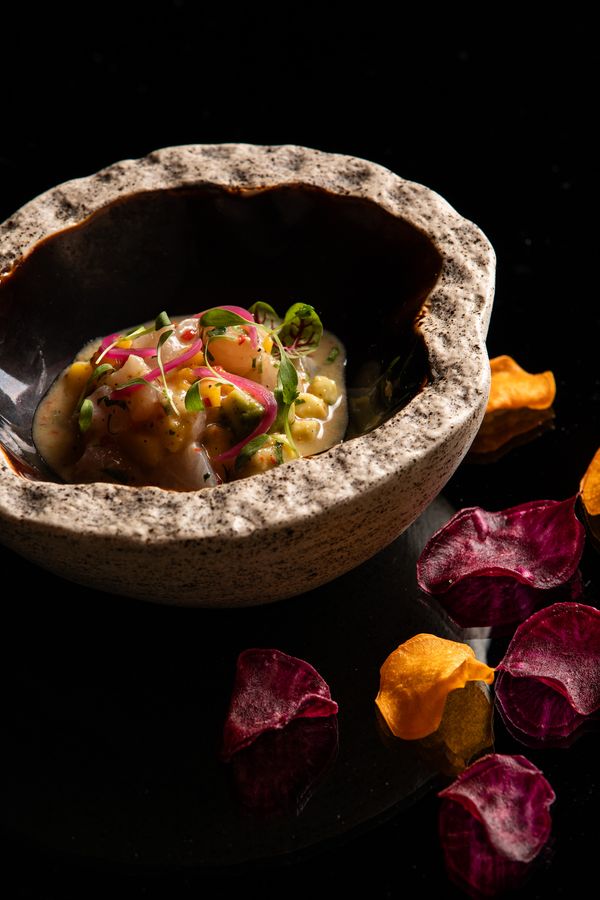 Peruvian ceviche in a stone bowl with purple and orange root crisps